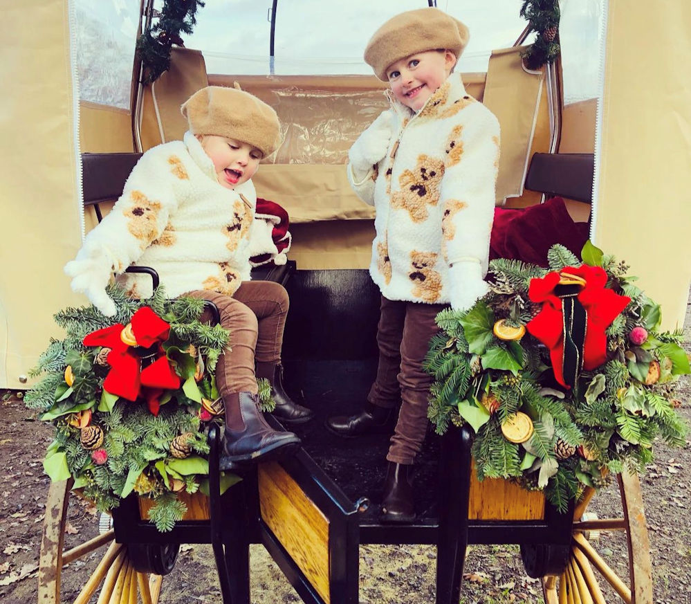 Two children on a carriage decorated for Christmas